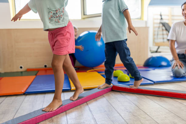 A physiotherapist working with two young kids on balance and coordination