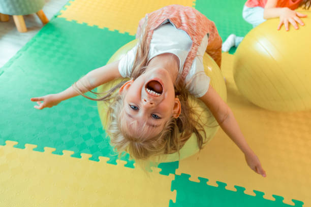 A girl balancing on gym ball. This is a fun and effective physiotherapy activity to improve core stability for kids